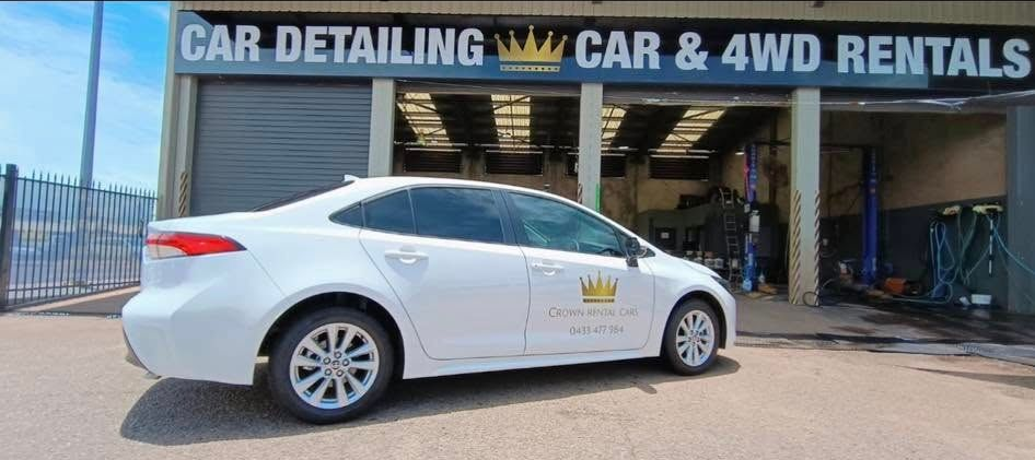 White car parked outside a car detailing and 4WD rental shop with a blue and white sign. — Crown Rental Cars in Nightcliff, NT