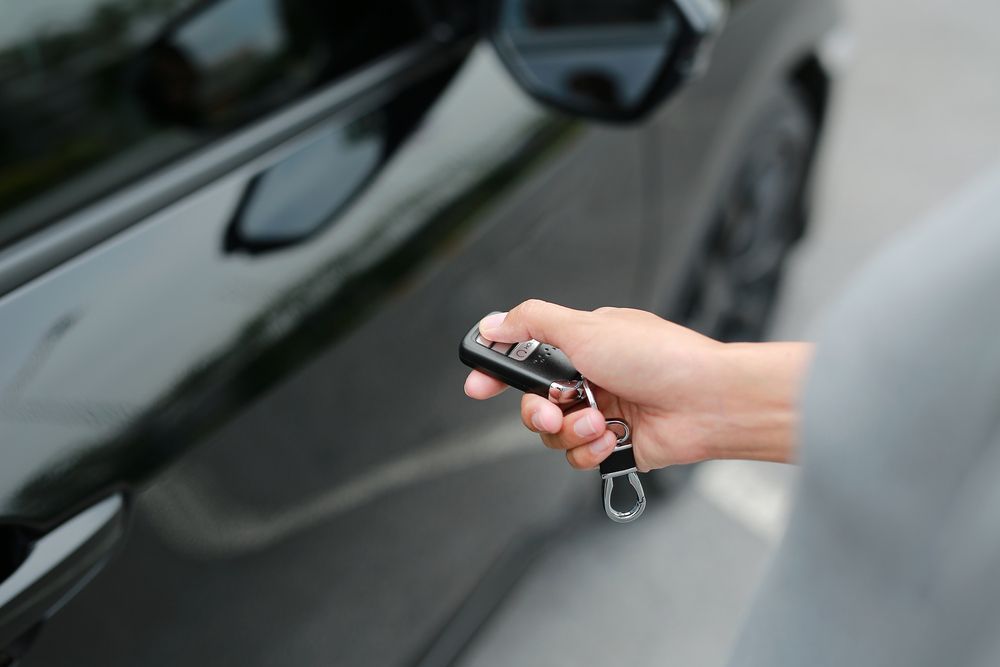 Hand Holding Car Key Fob, Unlocking a Black Car Door — Crown Rental Cars in Nightcliff, NT