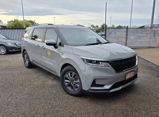 Grey Kia Carnival minivan parked on gravel. Cloudy sky in background.  — Crown Rental Cars in Nightcliff, NT