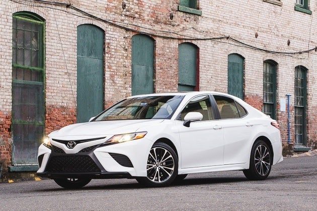 White Toyota Camry sedan parked on a street in front of a brick building. — Crown Rental Cars in Nightcliff, NT