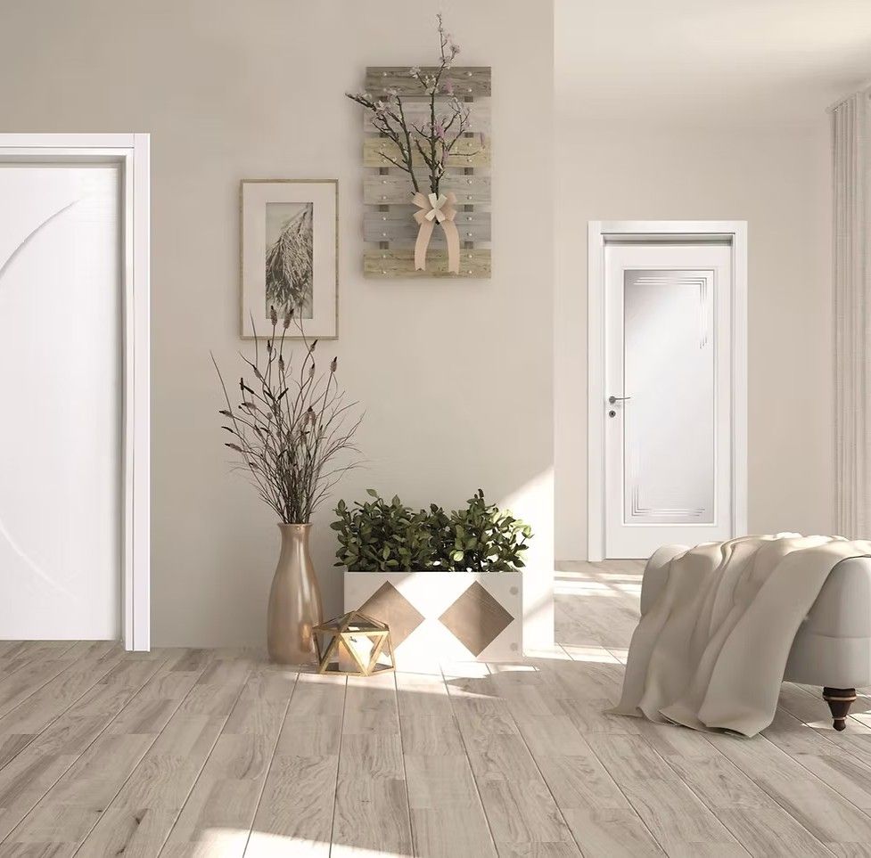 Interno con due porte bianche, opere d'arte, piante e pavimenti in legno.