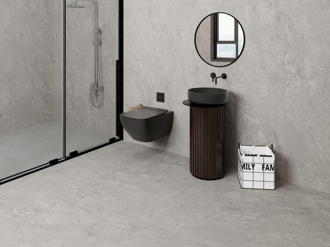 Moderno bagno grigio con WC sospeso, lavandino scuro e doccia in vetro.