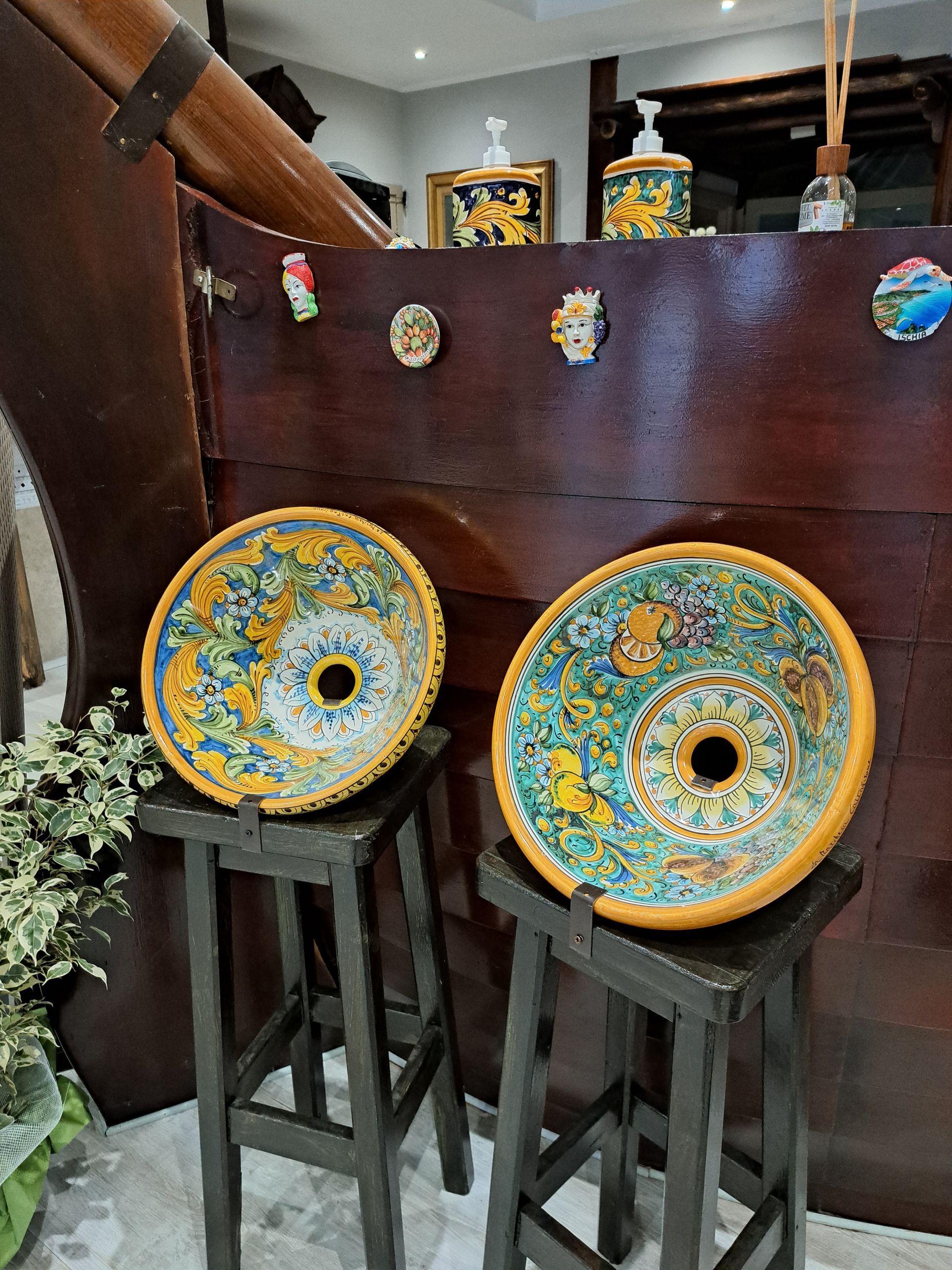 Due lavandini decorativi in ceramica su sgabelli di legno, caratterizzati da intricati disegni colorati.