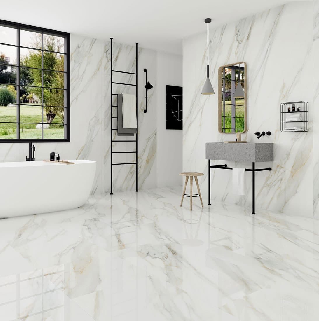 Lussuoso bagno in marmo bianco con ampia finestra che si affaccia sul giardino e vasca da bagno indipendente.