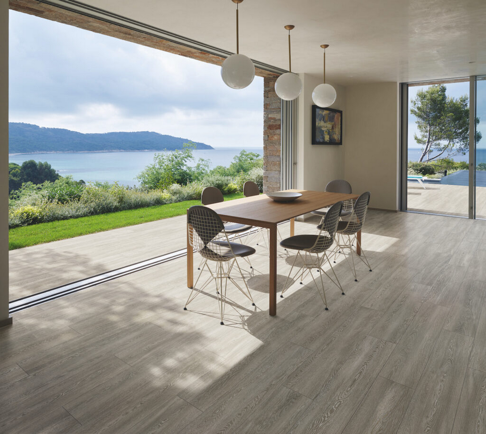 Sala da pranzo con pareti in vetro, tavolo in legno e vista sull'oceano.