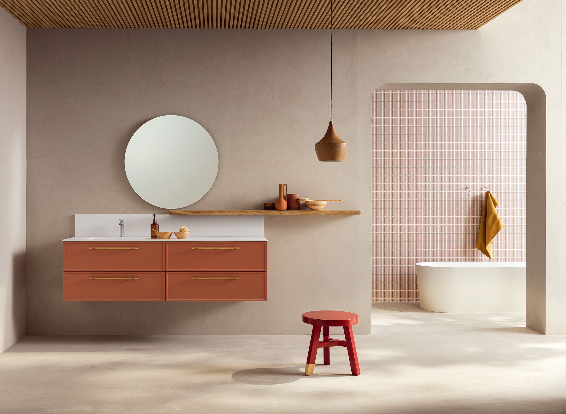 Bagno moderno con mobile lavabo arancione, specchio rotondo e doccia piastrellata rosa.