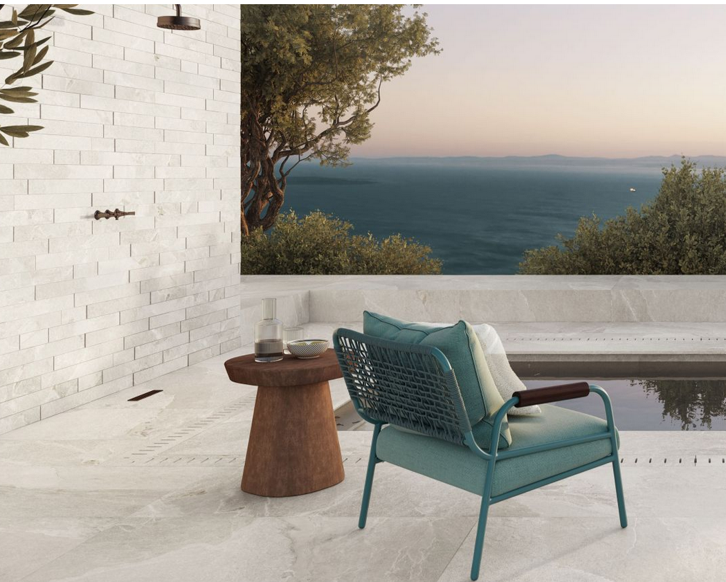 Doccia esterna con vista, dotata di sedia turchese, tavolino in legno e un sereno sfondo oceanico.