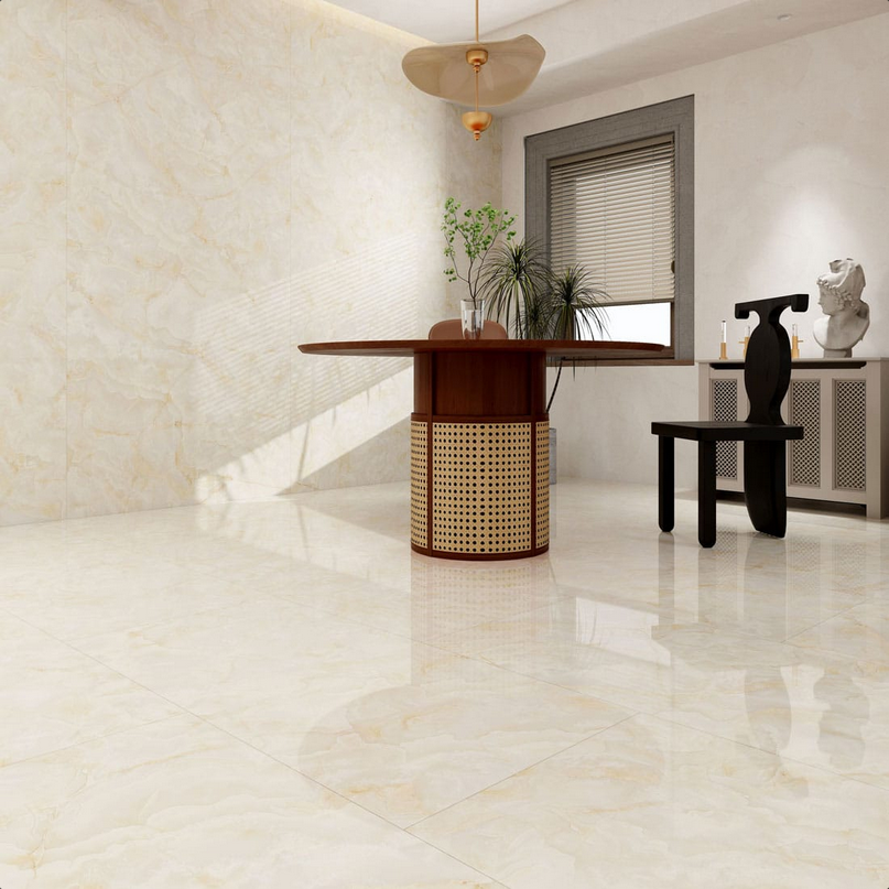 Stanza con pavimento beige lucido, tavolo rotondo in legno, base in rattan, piante e pareti bianche.