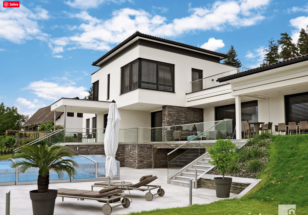 Moderna casa bianca con piscina, mobili da giardino e cielo azzurro.