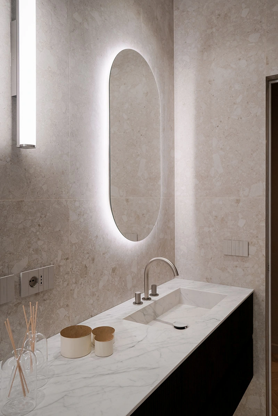 Bagno con carta da parati con foglie di palma, piano di lavoro bianco con doppi lavandini, doccia in vetro, pavimento in legno chiaro.