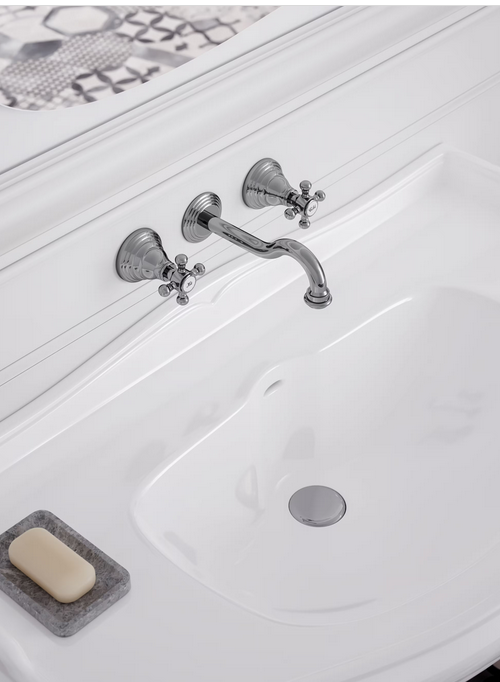 Lavandino bianco con rubinetto argentato decorato, portasapone con sapone.