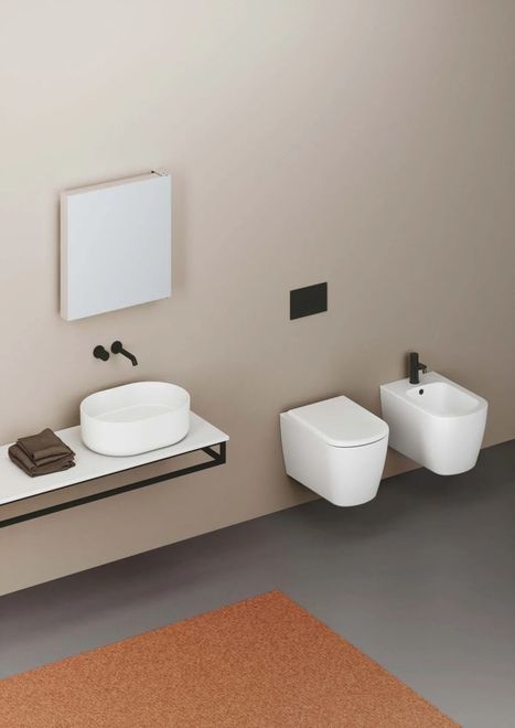 Bagno moderno con lavandino bianco, WC, bidet e sanitari neri contro una parete neutra.