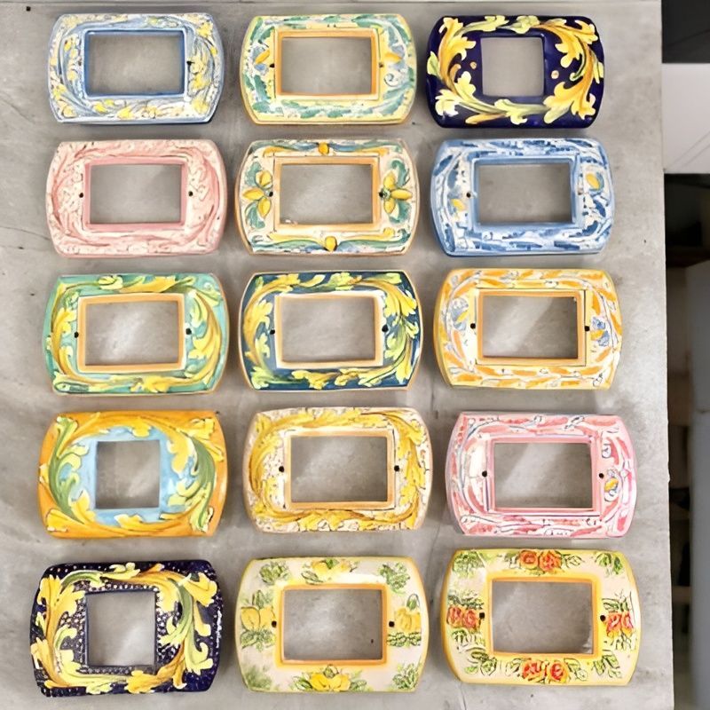 Placche per interruttori in ceramica dipinte a mano con vari motivi floreali e colori.