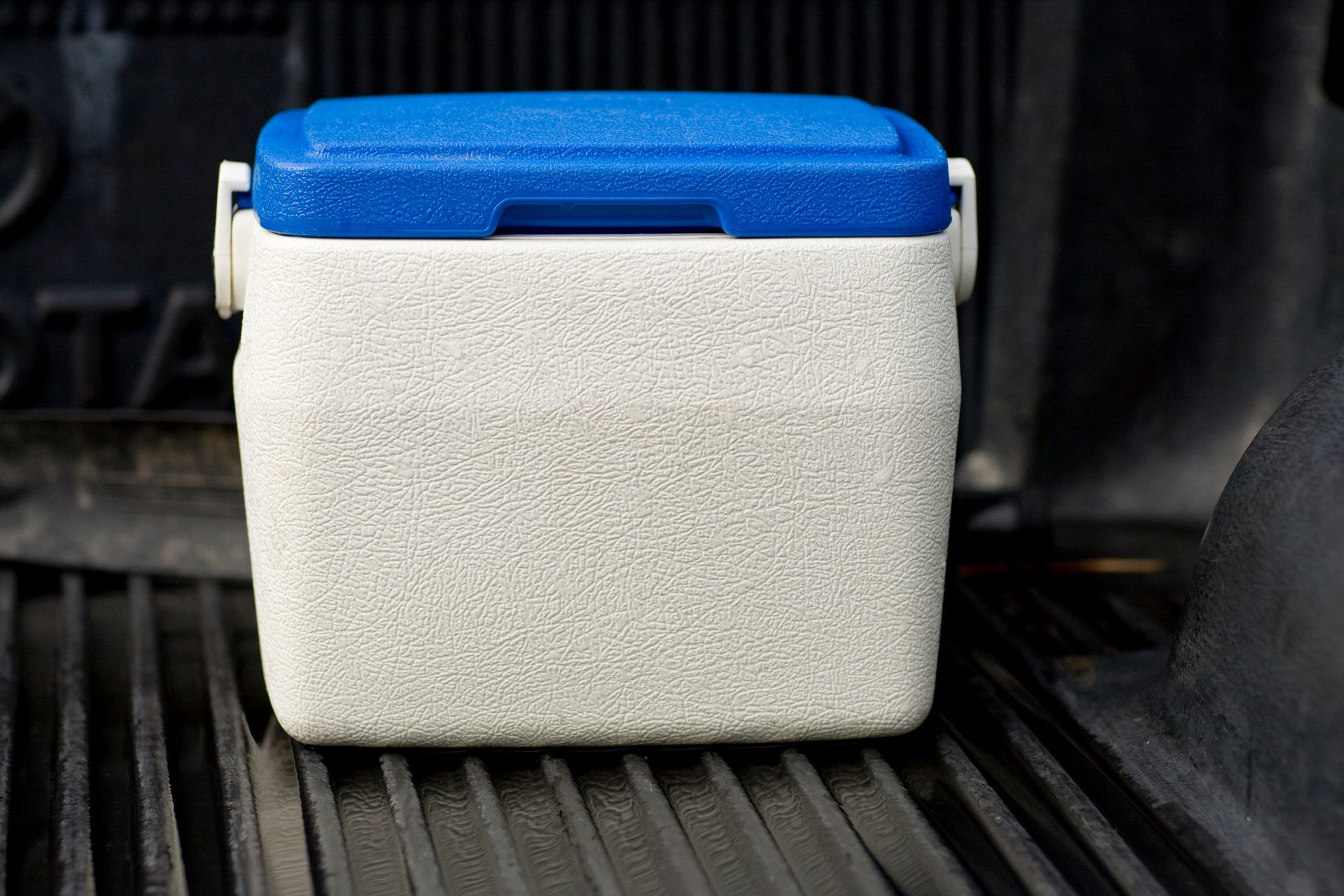 A small cooler is sitting on the back of a truck.