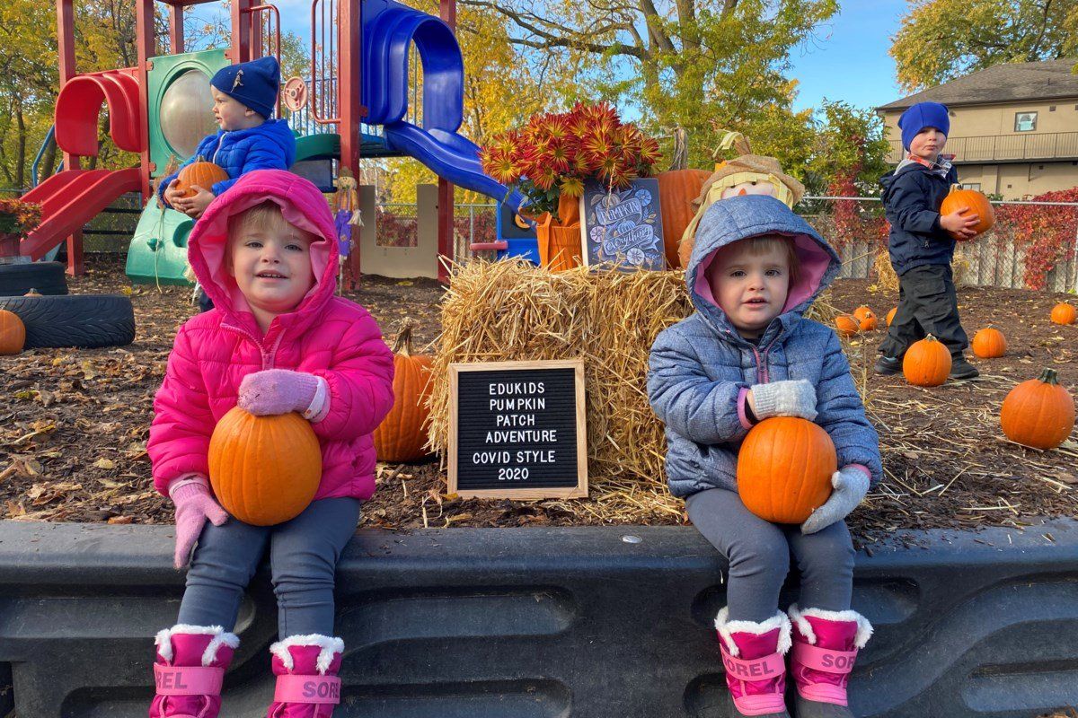 Two children holding pumpkins outisde in the playground