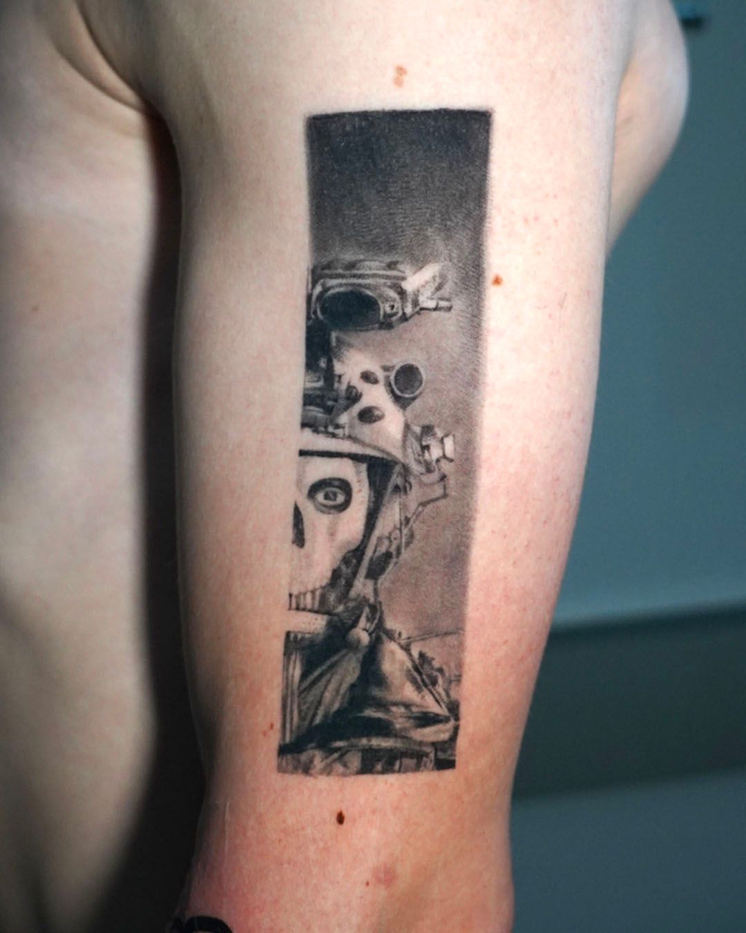A rectangular black-and-grey tattoo on an arm depicting the masked character Ghost from Call of Duty in tactical gear.