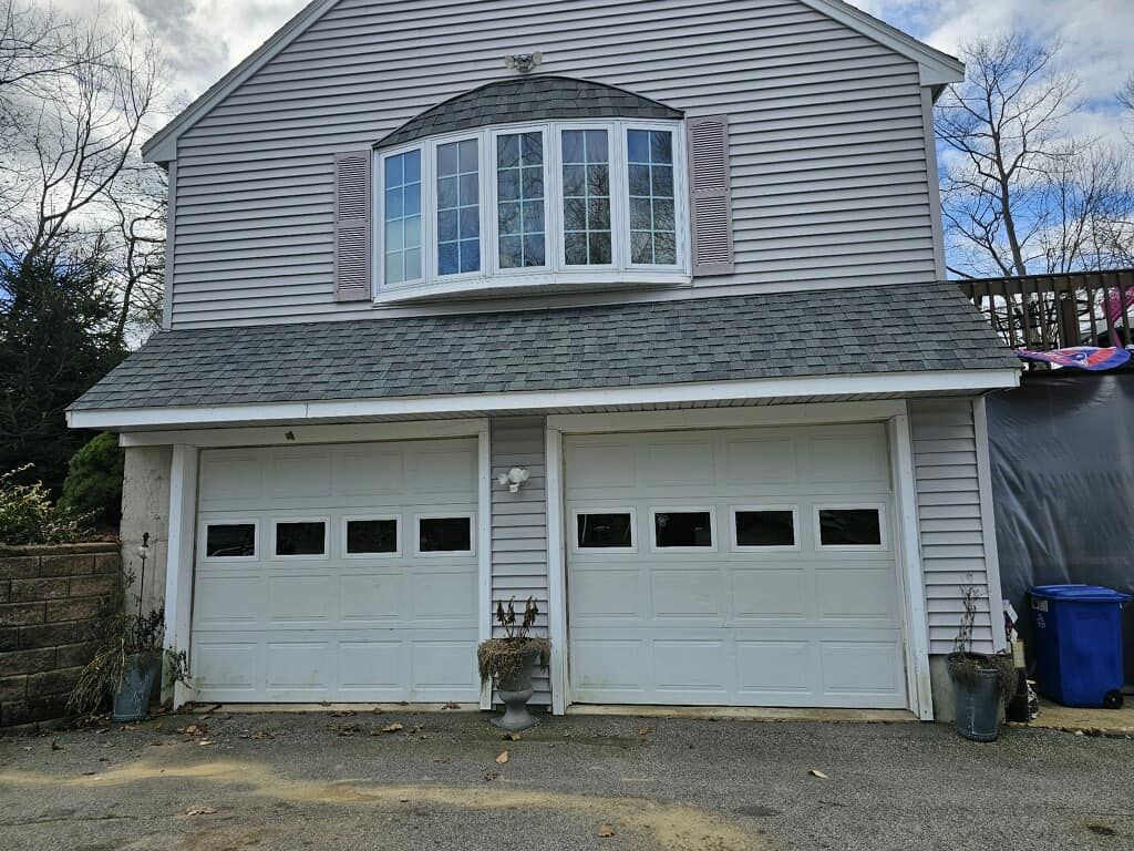 A large white house with two garage doors and a large window.
