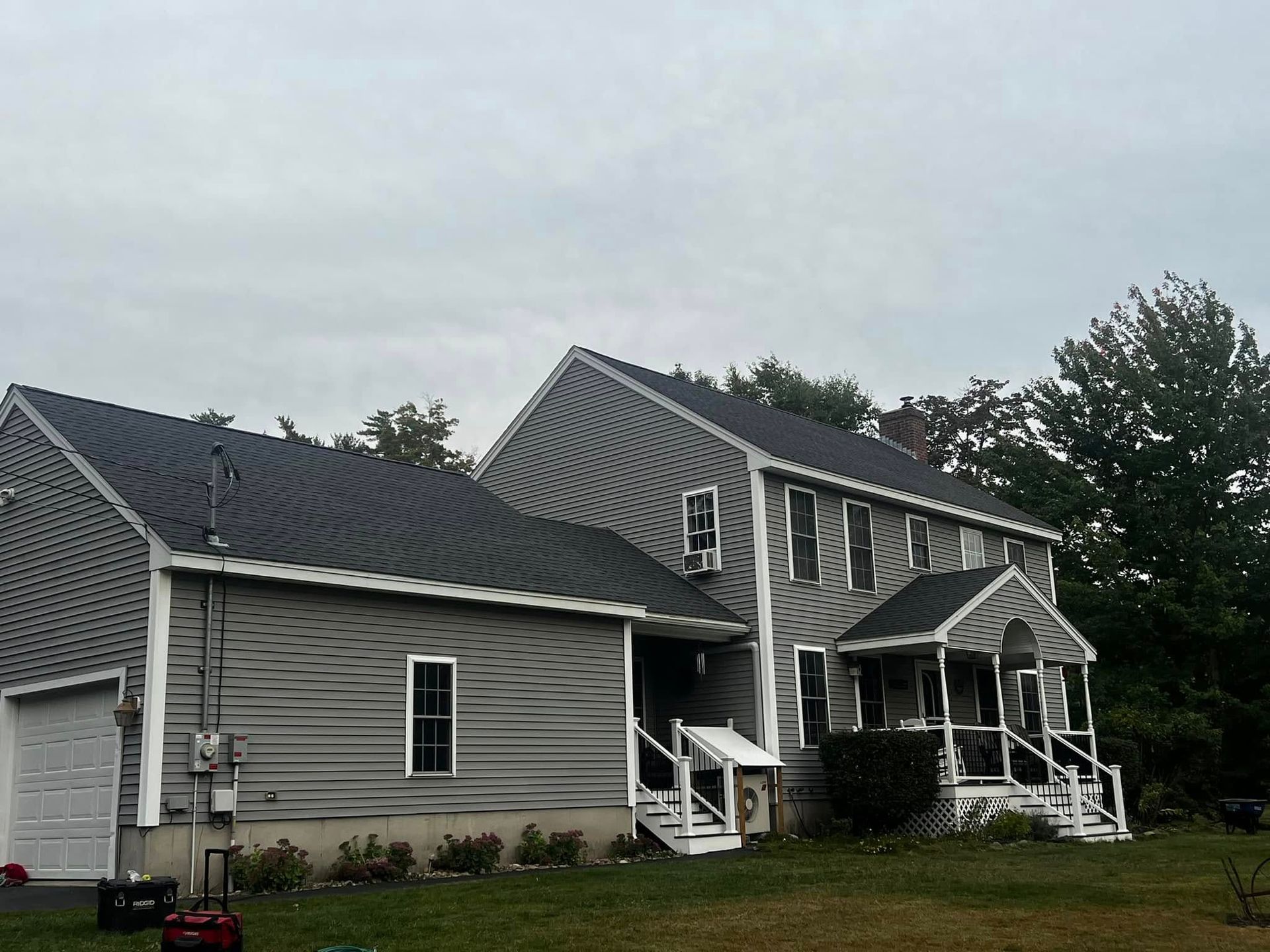 A gray house with a black roof and white trim