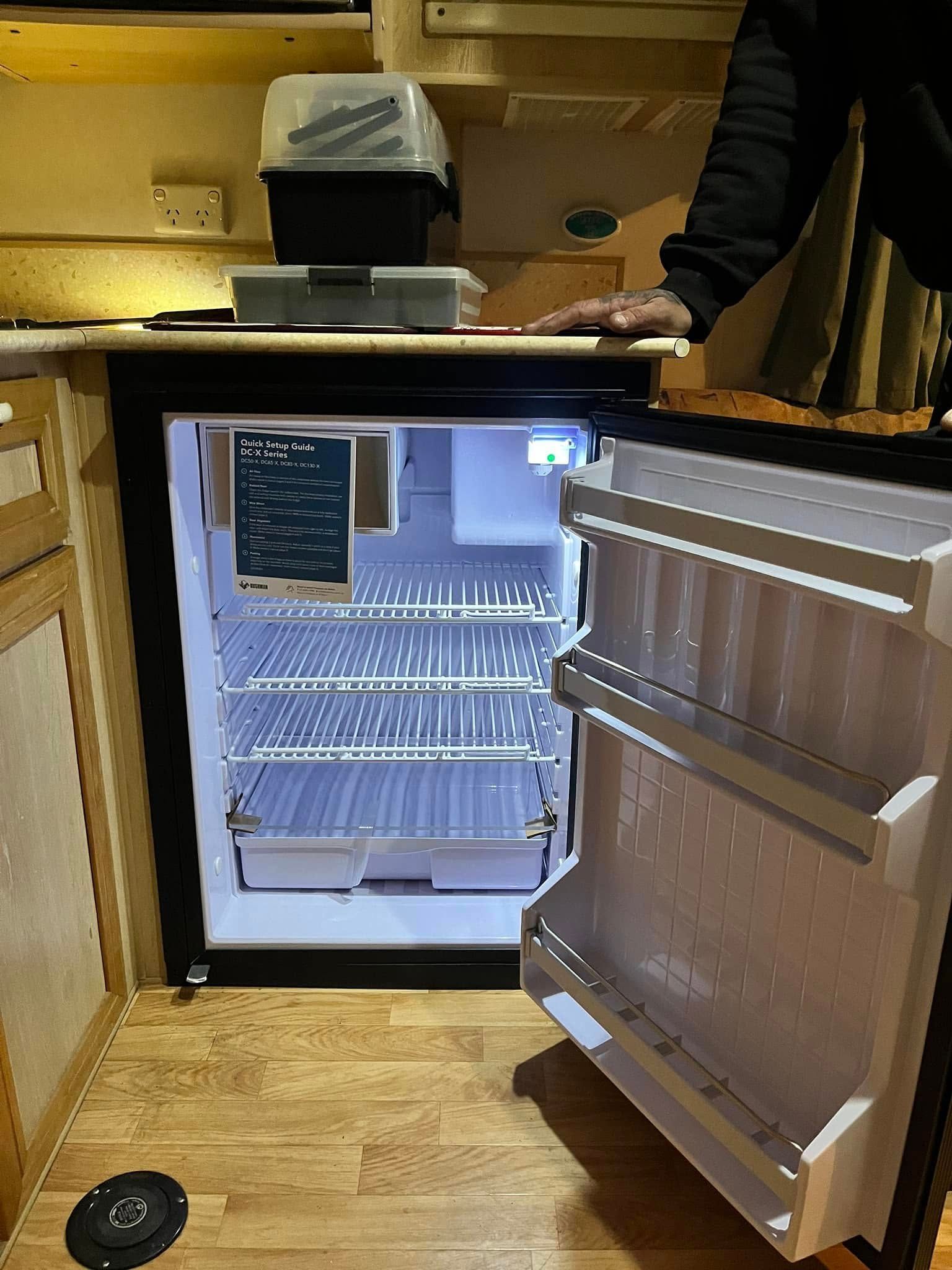 A Small Refrigerator With Its Door Open Inside A Wood-paneled Camper — Torque Metro Caravan Services in Archerfield, QLD