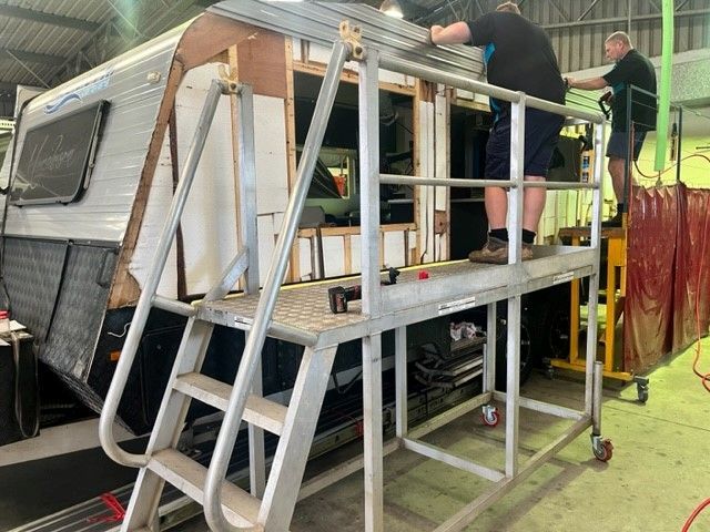Two Men Working On A Caravan. One On A Platform, Attaching Parts — Torque Metro Caravan Services in Archerfield, QLD