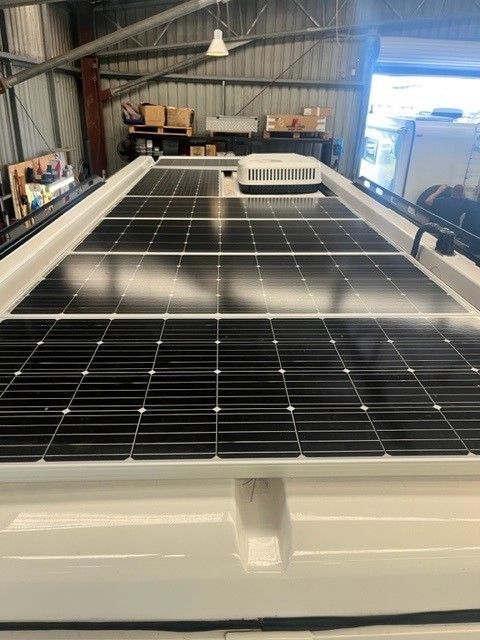 Solar Panels On A White Van Roof In A Workshop With Open Doors — Torque Metro Caravan Services in Archerfield, QLD