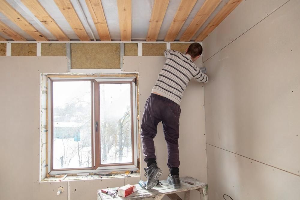 A man is working on a wall in a room.