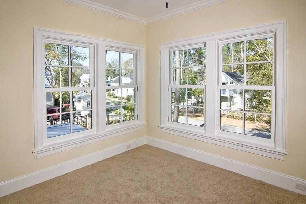 An empty room with three windows and a carpeted floor.