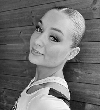 A black and white photo of a woman standing in front of a wooden wall.