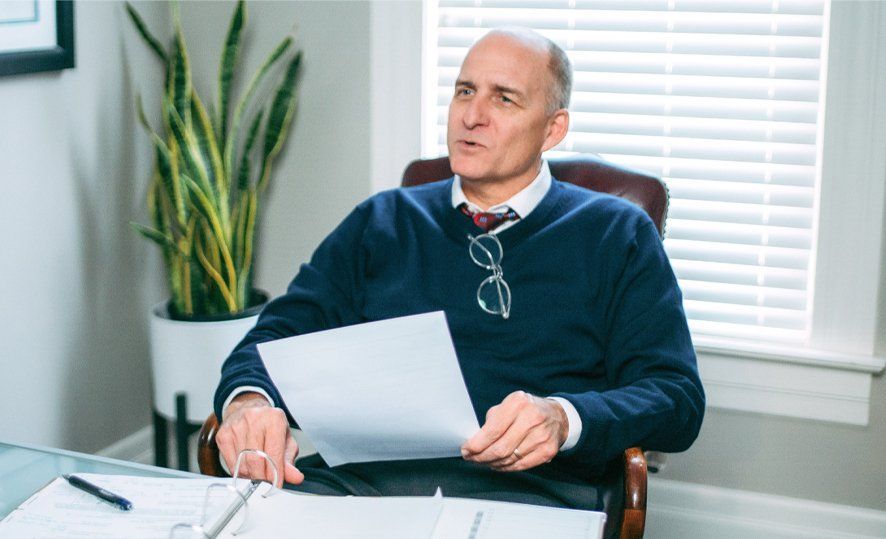 A man is sitting at a desk holding a piece of paper.