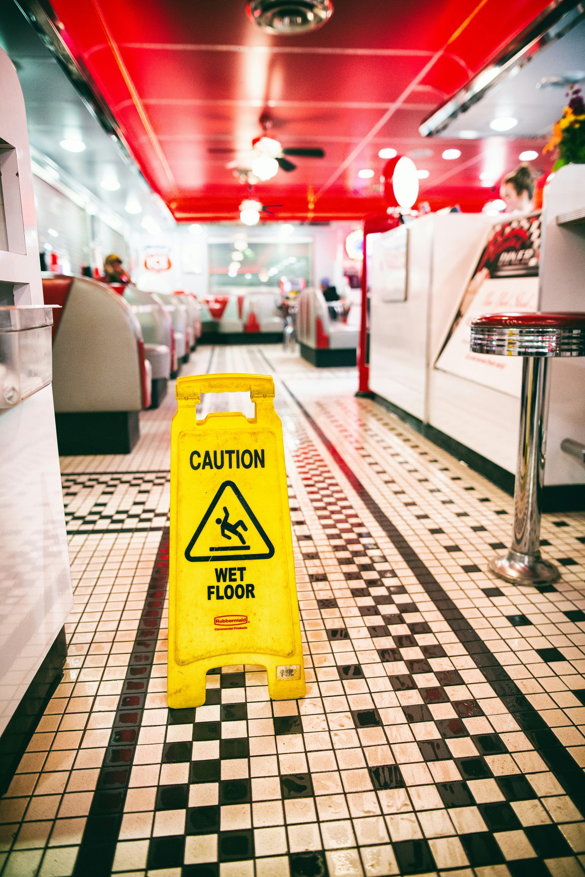 A yellow caution sign is on the floor of a diner.