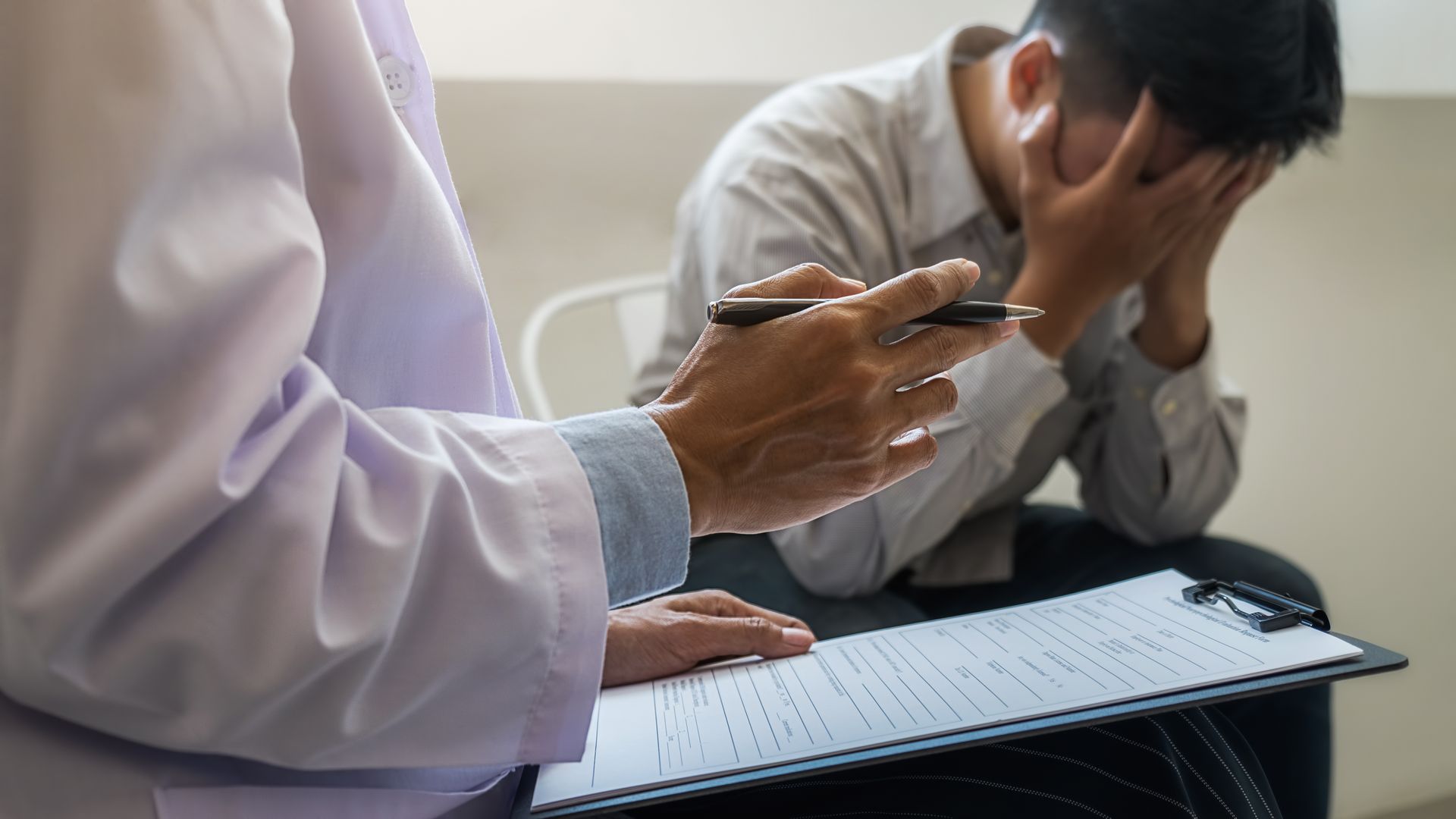 A doctor is talking to a patient who is sitting in front of a clipboard.