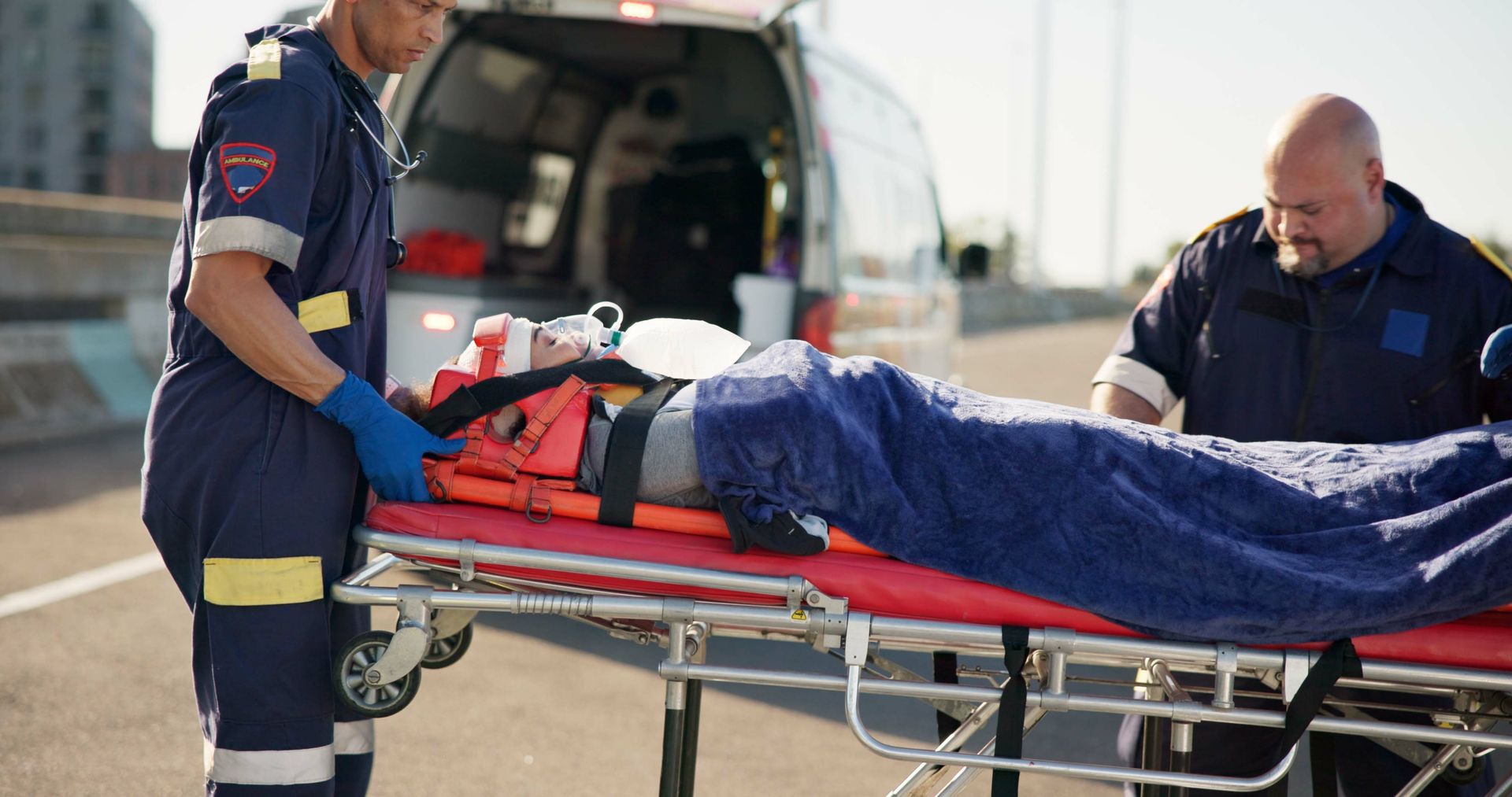 Two paramedics are carrying a patient on a stretcher to an ambulance.