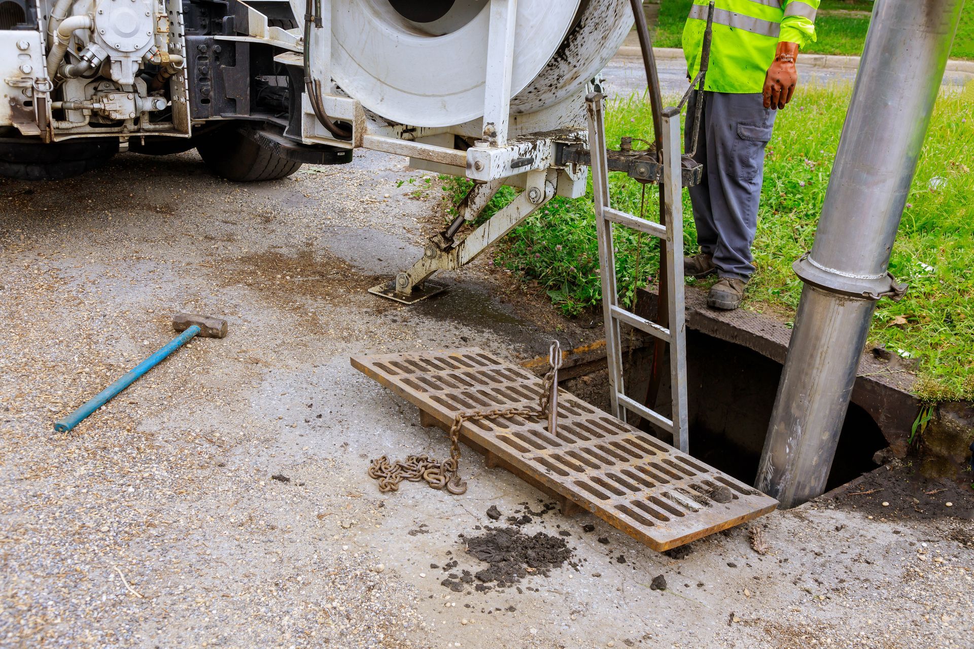 Construction worker beside concrete truck and open storm drain on gravel road