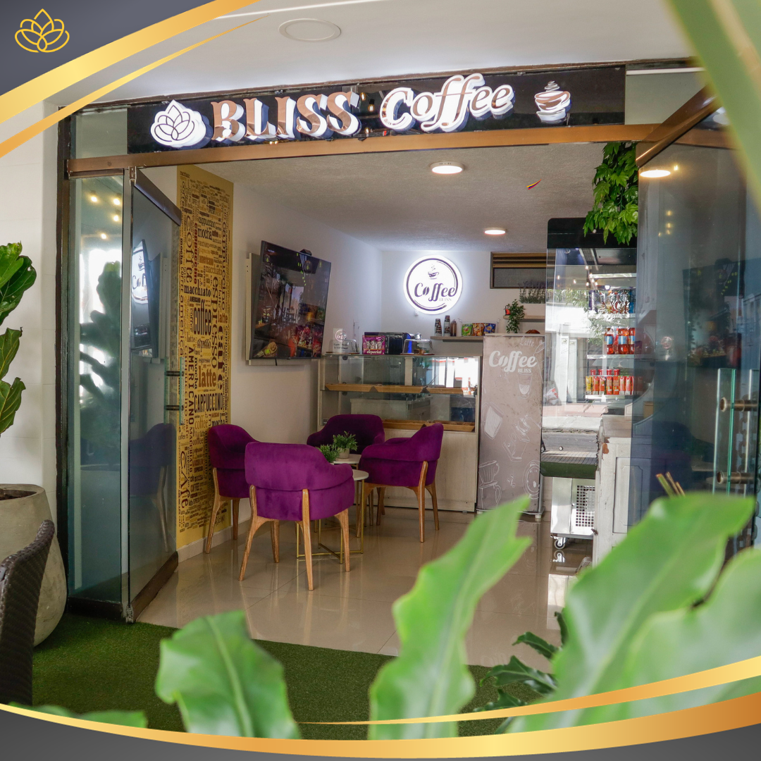 La entrada a la cafetería Bliss con sillas de terciopelo morado y un interior moderno y minimalista.