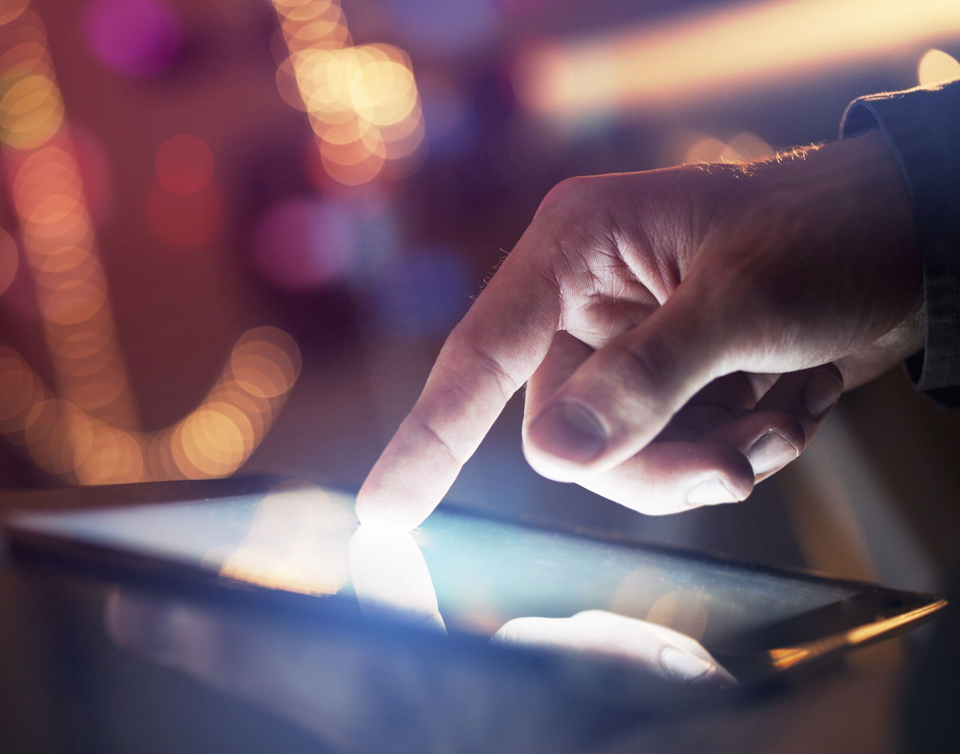 A person is pointing at a tablet with their finger.