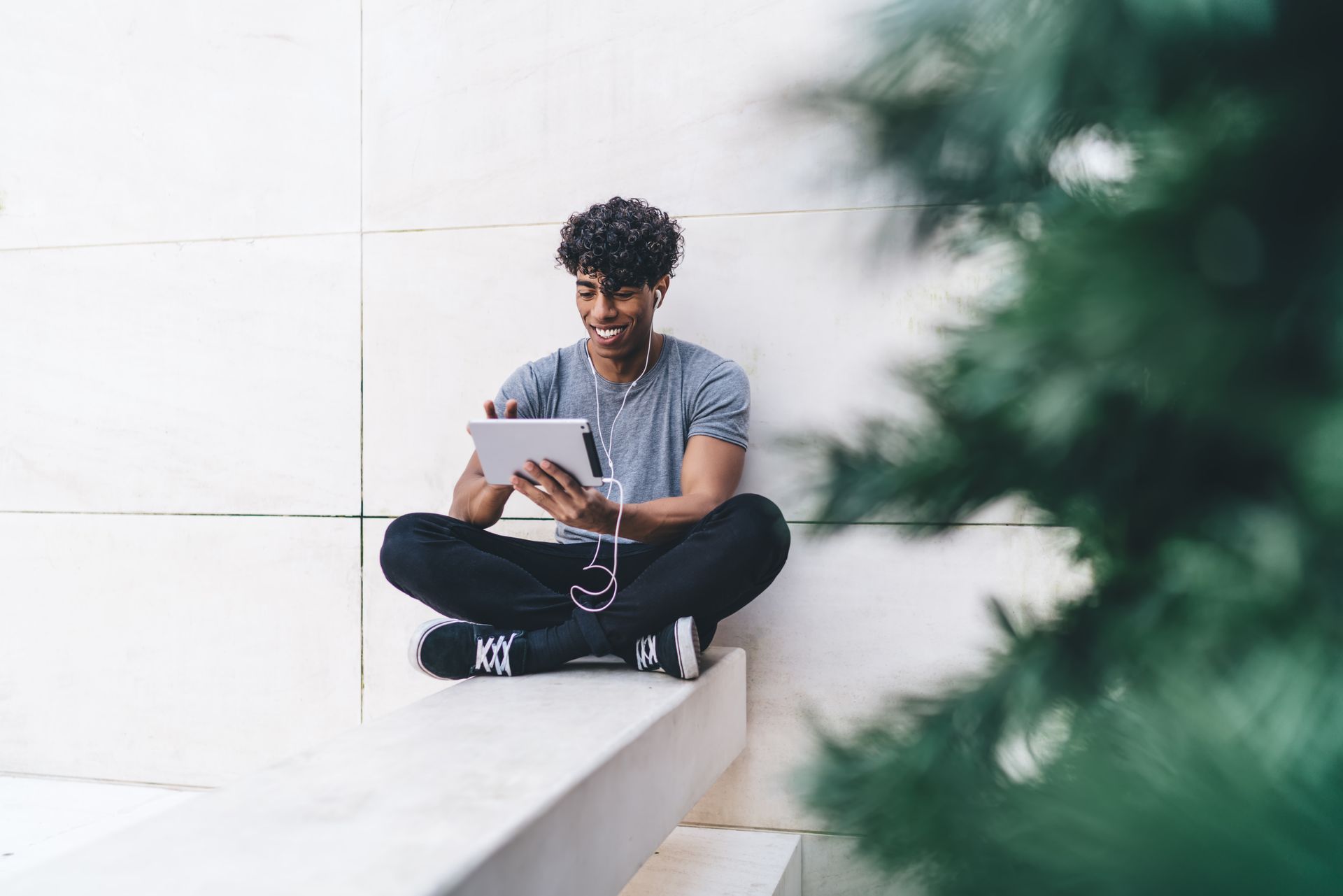 A man is sitting on the ground using a tablet computer.