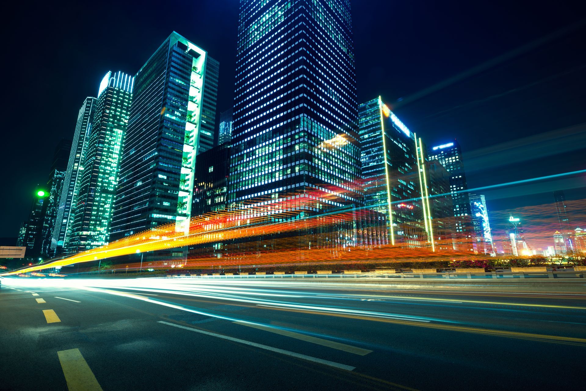 A long exposure of a city at night with a highway in the foreground.