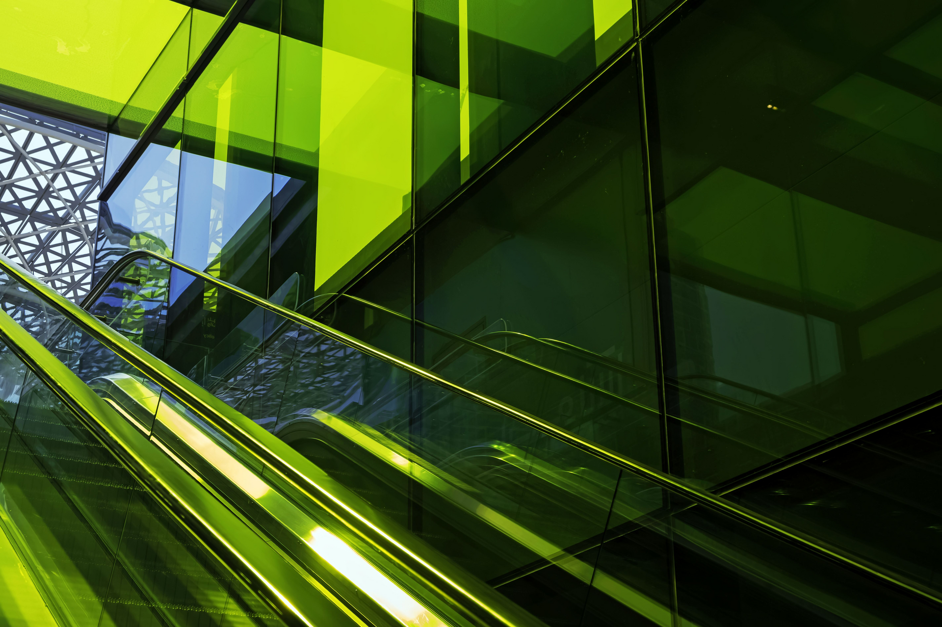 A green escalator in front of a green building