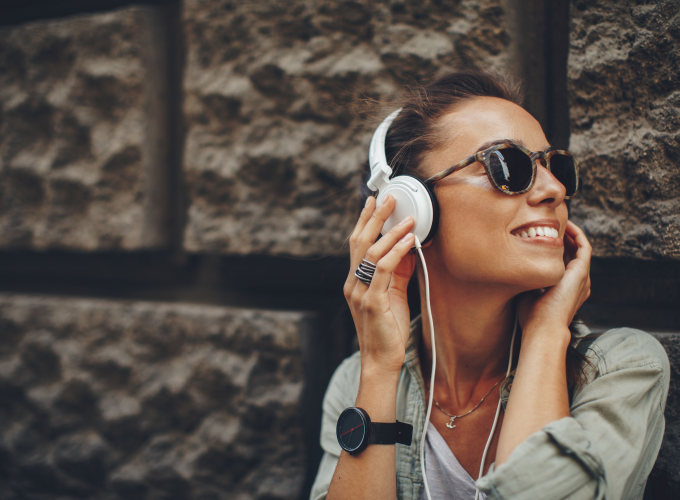 A woman wearing sunglasses and headphones is listening to music.