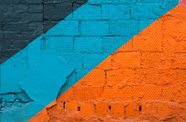 A brick wall with two different colors painted on it.
