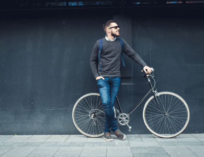 A man is leaning against a wall next to a bicycle.