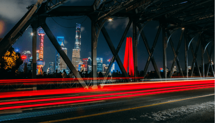 A bridge over a river with a city in the background at night.