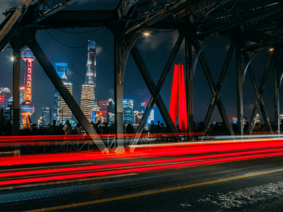 A bridge over a river with a city in the background at night.