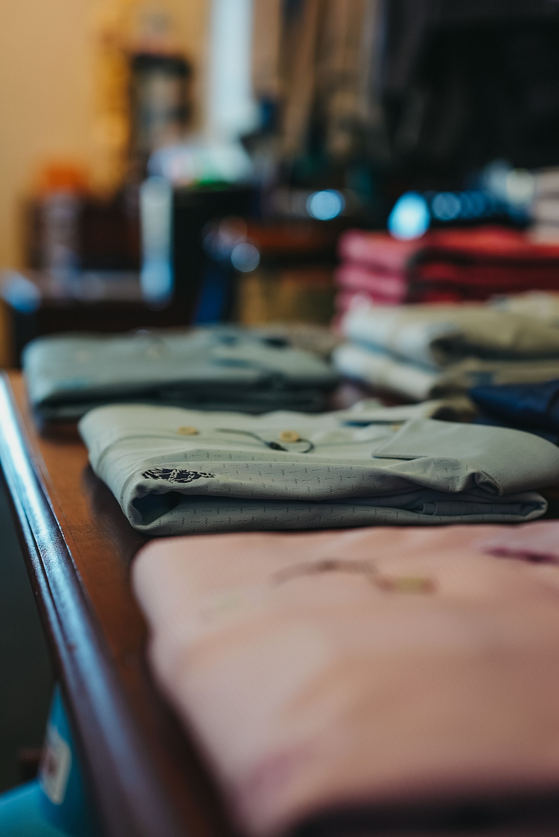 Folded clothes on a brown table, various pastel colors visible.