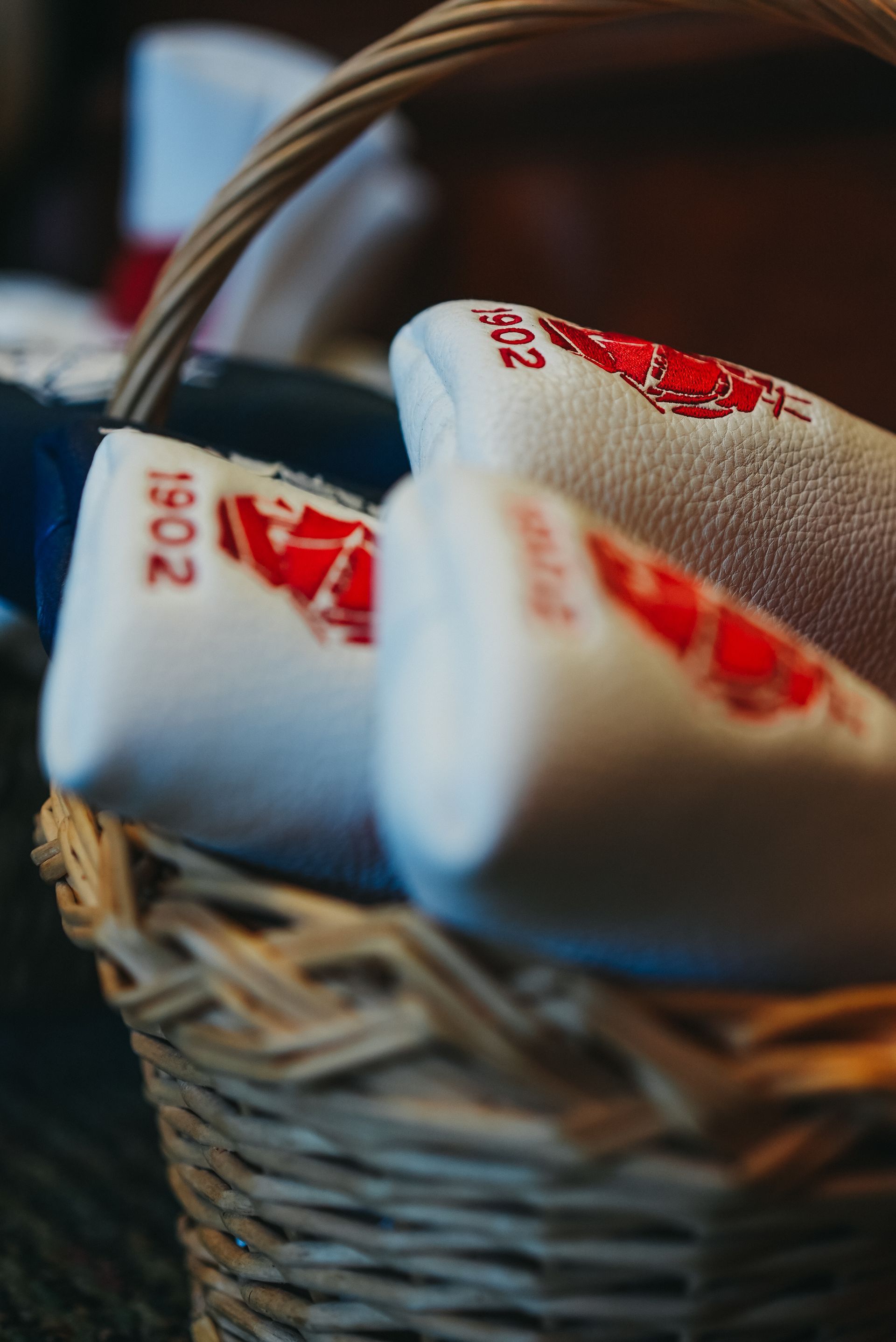 Close-up of a wicker basket filled with white towels embroidered with red designs and text.