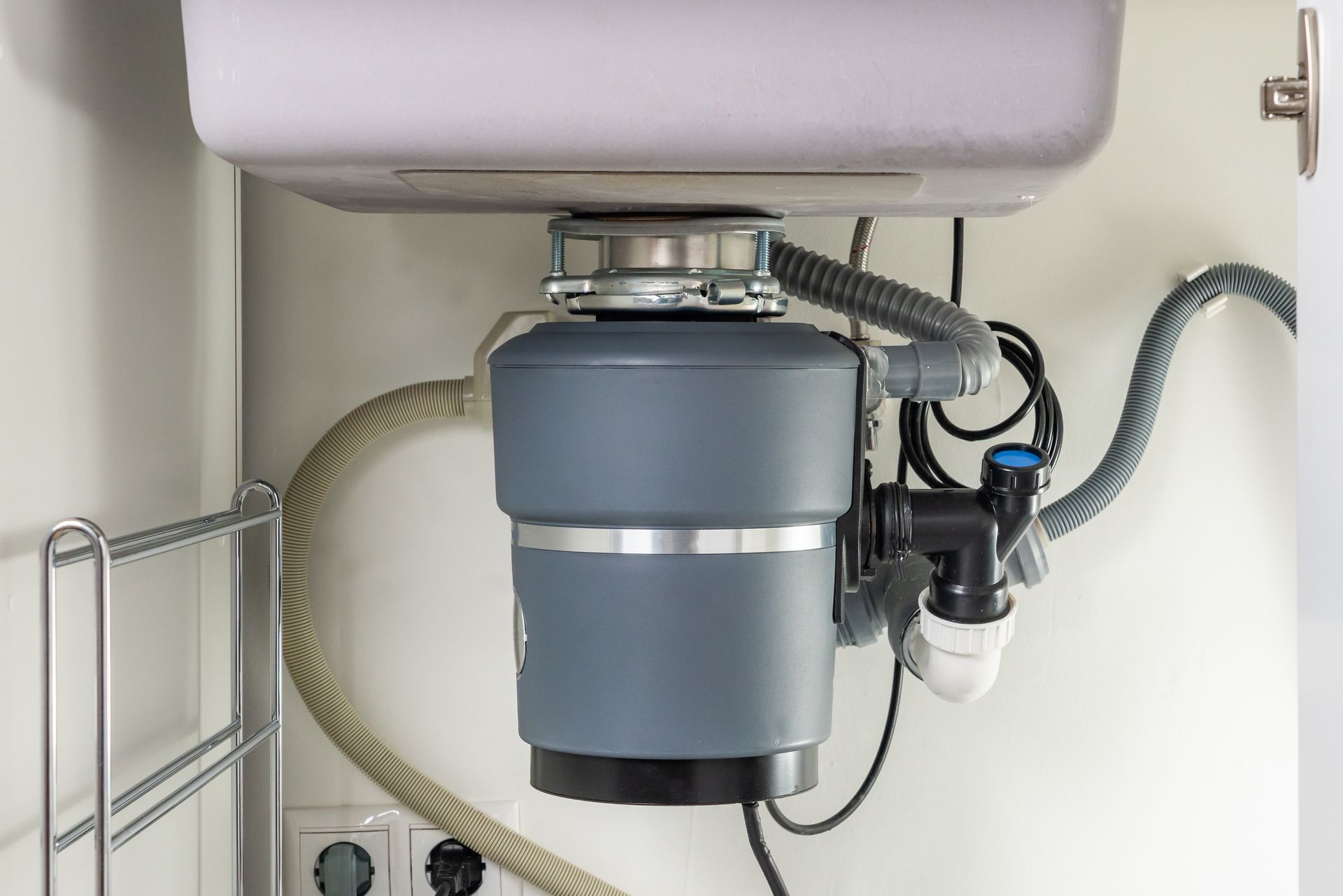Under-sink garbage disposal with gray motor and connected plumbing hoses