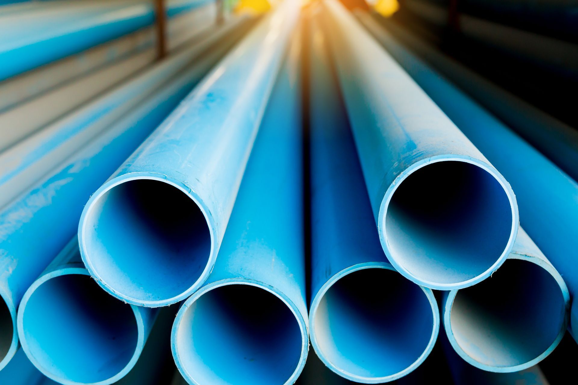 Stacked blue plastic pipes with open circular ends in an industrial setting