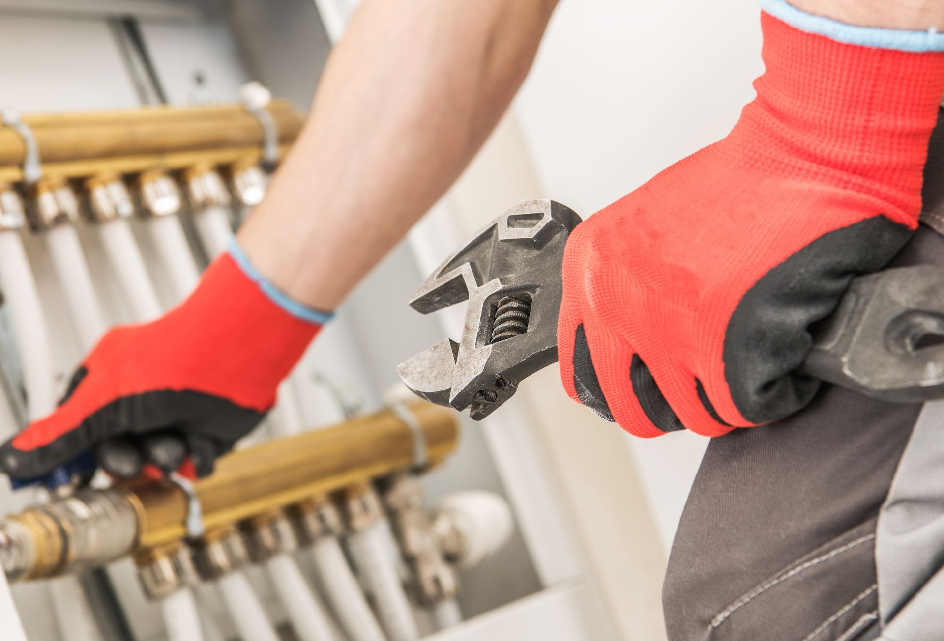 Hands adjusting a chrome sink faucet with pliers in a bright kitchen sink area
