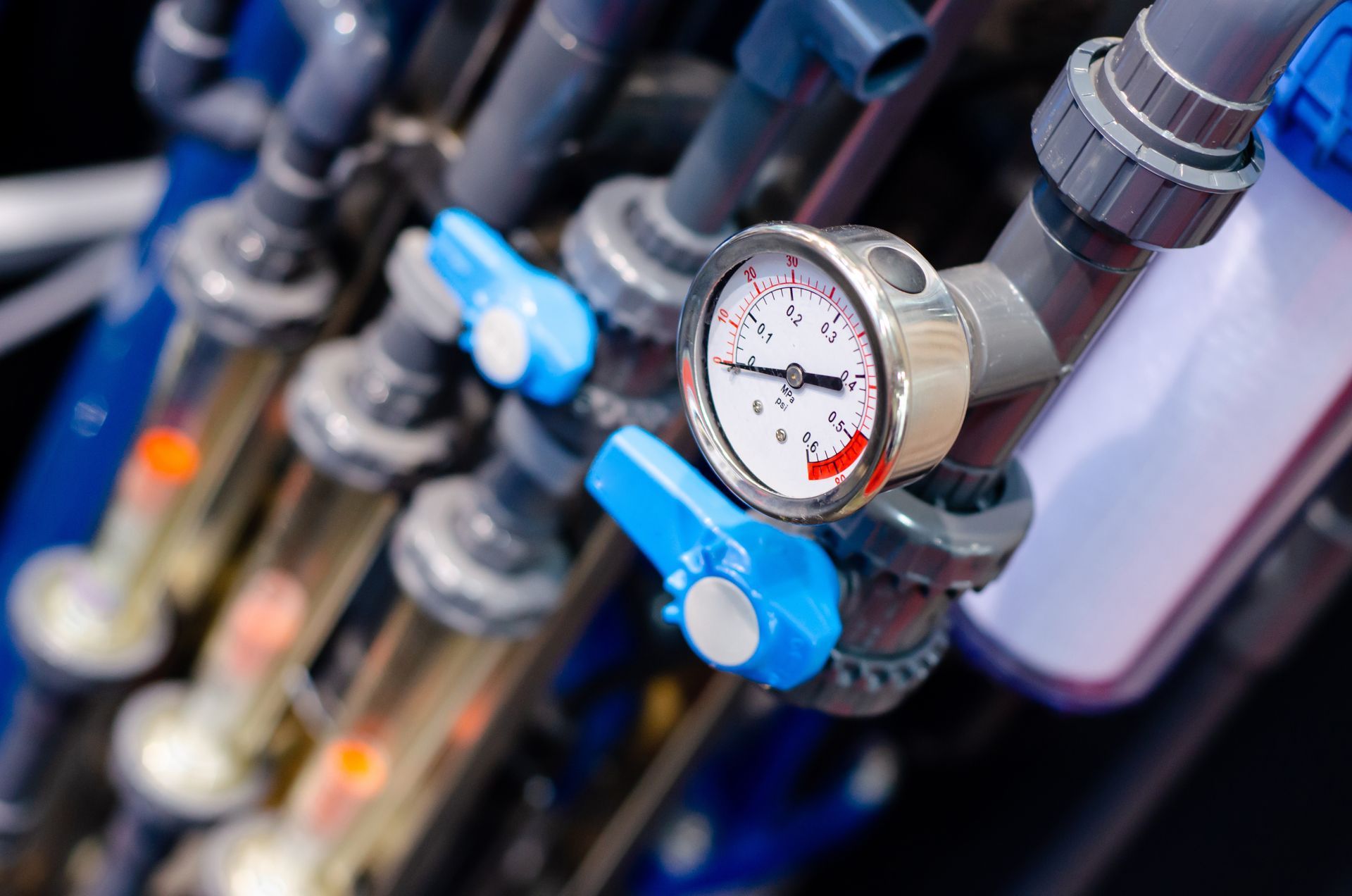Industrial pressure gauge with blue valves and pipes in a mechanical system
