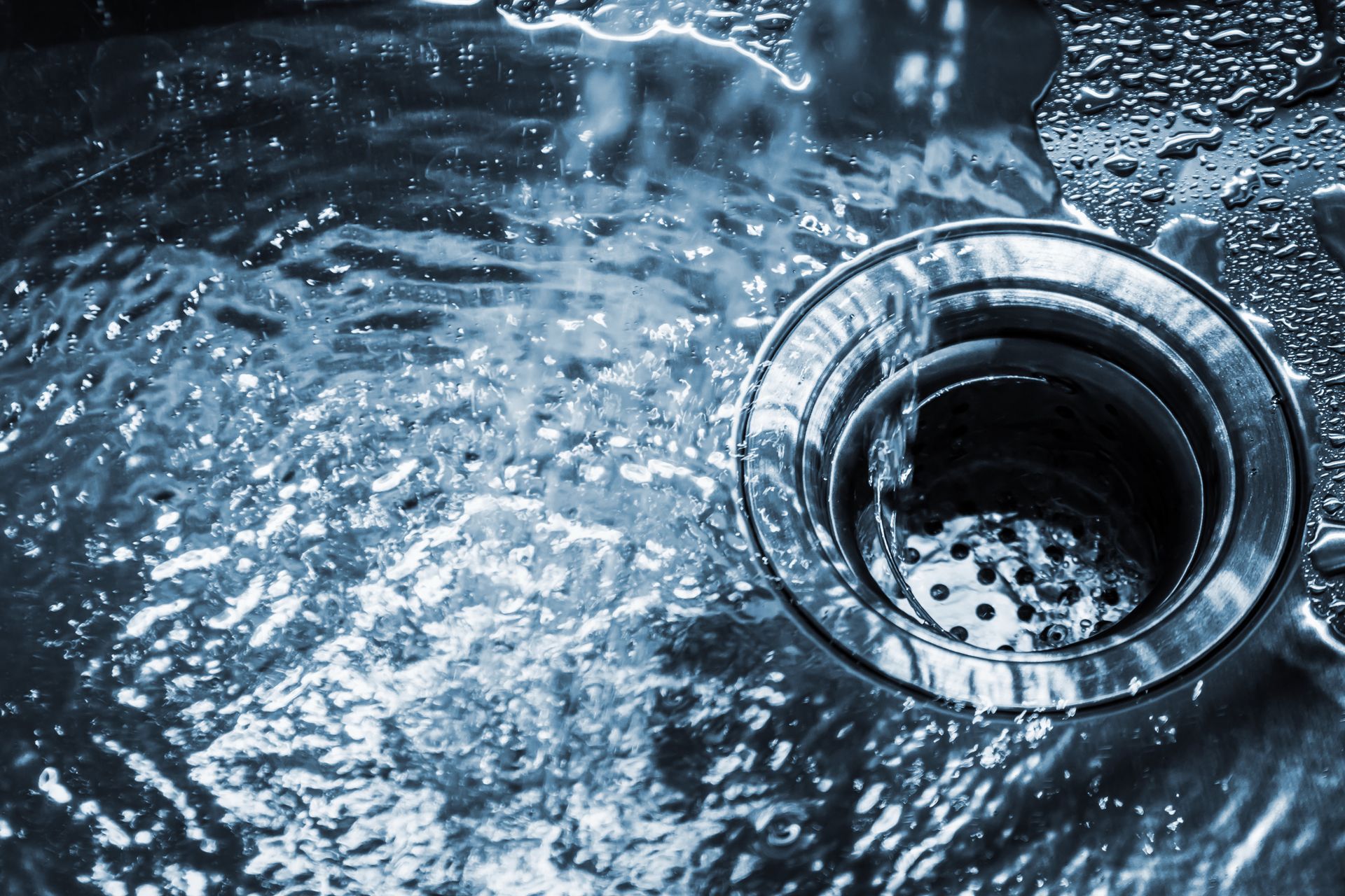 Close-up of water swirling into a stainless steel sink drain